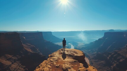 The image shows a person standing on a cliff, looking out at a vast canyon landscape.