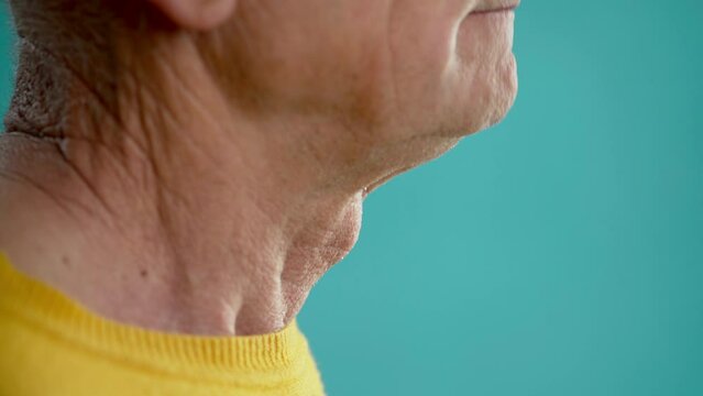 Side view of an old man swallowing food, throat and larynx close up