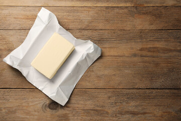 Block of tasty butter on wooden table, top view. Space for text