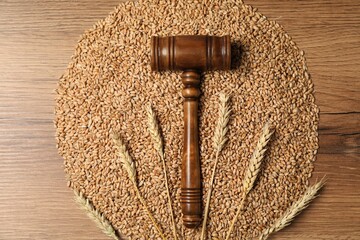 Judge's gavel, wheat ears and grains on wooden table, top view. Agricultural deal