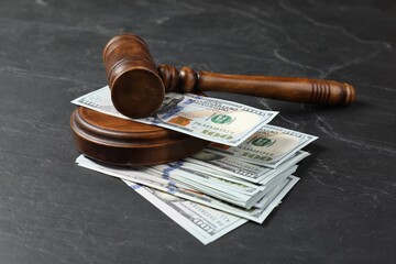 Judge's gavel and money on dark grey table
