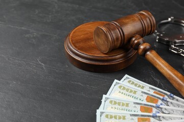 Judge's gavel, money and handcuffs on dark grey table, closeup. Space for text
