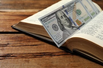 Open Bible with money on wooden table, closeup