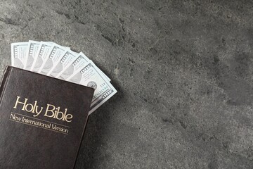 Holy Bible and money on grey table, top view. Space for text