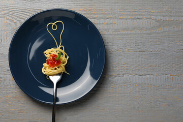 Heart made with spaghetti and fork on grey wooden table, top view. Space for text