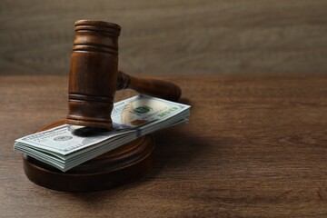 Law gavel with stack of dollars on wooden table, closeup. Space for text