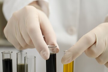 Laboratory worker holding test tubes with different types of crude oil, closeup