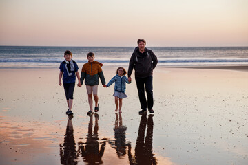 Portrait silhouettes of three children and dad happy kids with father on beach at sunset. happy family, Man, two school boys and one little preschool girl. Siblings having fun together. Bonding