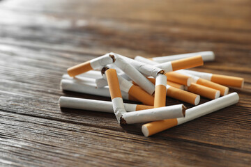 Stop smoking. Pile of whole and broken cigarettes on wooden table, closeup