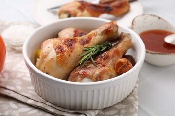 Marinade, roasted chicken drumsticks, rosemary and tomatoes on white table, closeup