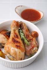 Marinade, roasted chicken drumsticks, rosemary and tomatoes on white tiled table, closeup