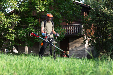 Man using a trimmer to cut grass in yard - 796792321