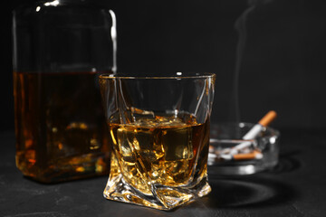 Alcohol addiction. Whiskey in glass on dark textured table, closeup