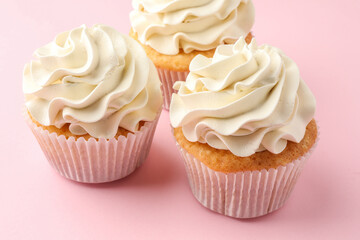 Tasty vanilla cupcakes with cream on pink table, closeup