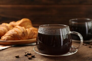 Hot coffee in glass cup and beans on wooden table, closeup