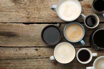 Different coffee drinks in cups on wooden table, flat lay. Space for text