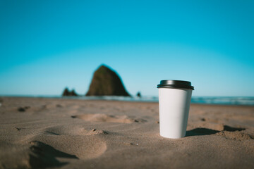 A blank coffee cup by haystack rock. 