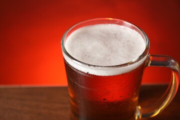 Mug with fresh beer on table against red background, closeup. Space for text