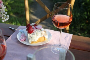 Naklejka premium Glass of wine and cake on table served for romantic date in garden