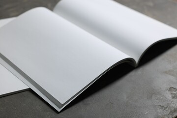 Open notebook with blank paper sheets on grey textured table, closeup. Mockup for design