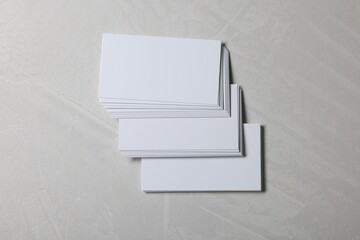 Blank business cards on light grey textured background, top view. Mockup for design