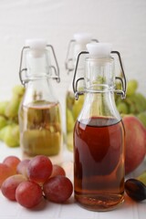 Different types of vinegar and ingredients on light tiled table, closeup