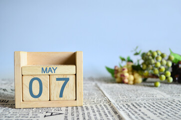 May 7, Calendar cover design with number cube with fruit on newspaper fabric and blue background.