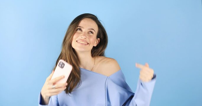 Happy woman, phone and dance for good news on blue background in celebration. Excited female person dancing with smile and smartphone for winning, sale or discount on.