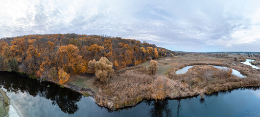 Aerial golden autumnal river panorama with autumn forest and scenic cloudscape