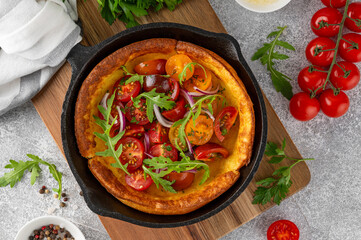Savory cheese Dutch baby pancake. Dutch Baby pancake with mix tomatoes, parsley and arugula in cast...