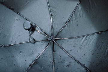 Black wet umbrella, with small water droplets from inside, umbrella spokes. Bad weather forecast,...
