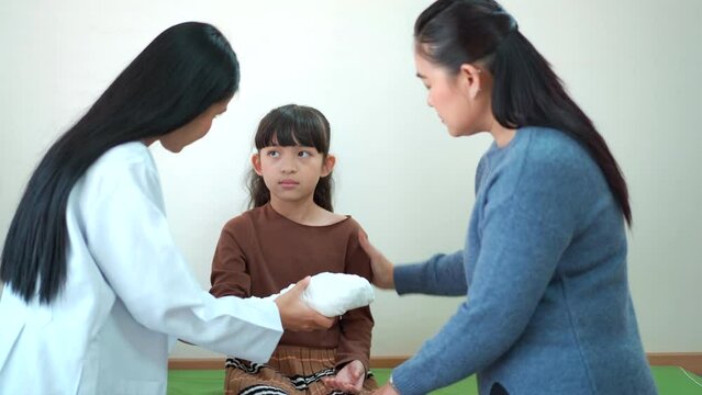 Mother brings her daughter to see an orthopedic doctor in hospital to have a discussion and consulting about her broken arm in splint cast.