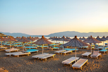 Straw umbrellas and sunbeds on the beach against the background of the sea in the morning