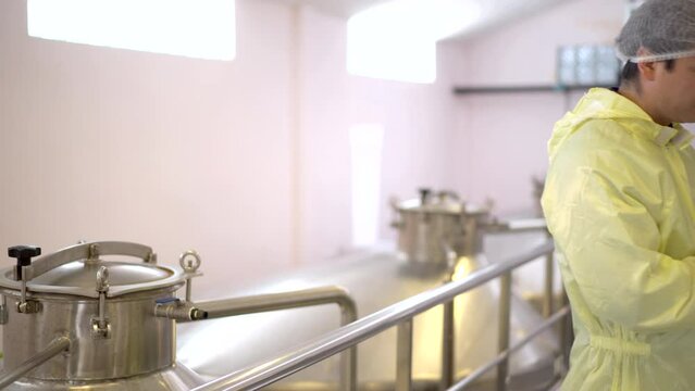 quality control officer is inspecting and checking food and beverage production machinery inside the manufacturing plant.