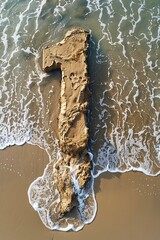 Intricate number 1 sand sculpture caressed by sea waves, perfect for themes of celebration and time by the ocean.