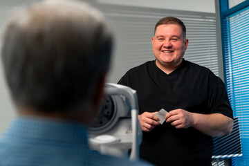 In an ophthalmology clinic an obese doctor says the results of eye diagnostics and smiles