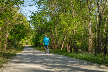 Male cyclist is riding a folding bike on Katy Trail near Rocheport, Missouri, spring scenery. The Katy Trail is 237 mile bike trail converted from an old railroad. - 796817914