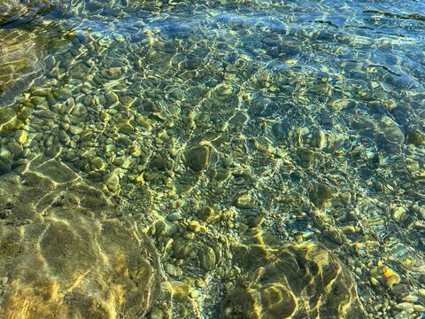 Sea stones and pebbles in transparent clear water.
