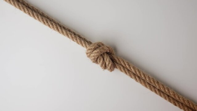Old thick ropes twisted and tied up creating knot, isolated on white background, close up shot. Two ropes tied in a knot, top view.