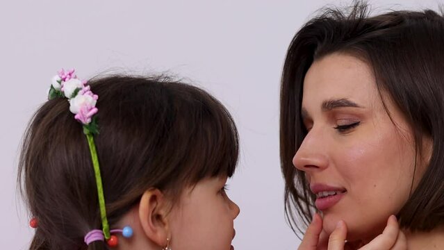 mother and 2 girls in bedroom, kissing and hugging eachother.mom and daughters jumping on mattress.kids and woman in pink dresses,many flowers on floor.international mother women day.vertical video