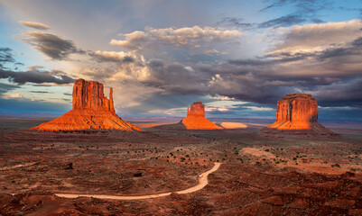 Monument Valley Buttes during an orange sunset captures the beauty of the valley expanse.
