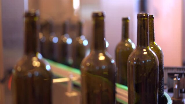 Footage showing an empty glass bottles are rolling on the alcohol bottling belt machine in the manufacturing facility. 