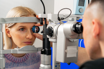 close up in an ophthalmology clinic young doctor diagnoses the eyes of a young girl with a...