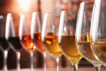 Different tasty wines in glasses against blurred background
