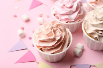 Delicious birthday cupcakes, bunting flags, marshmallows and sprinkles on pink background, closeup