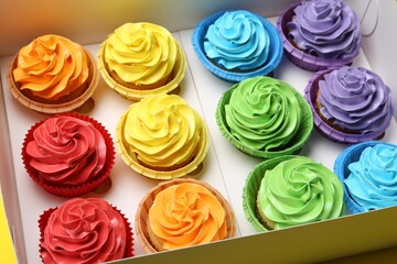 Many tasty cupcakes with colorful cream in box, closeup