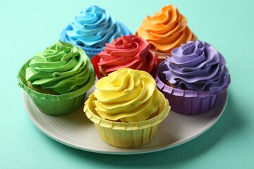 Plate with delicious bright cupcakes on turquoise background, closeup