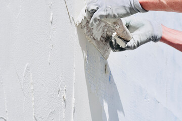 Man at work put mortar on top mesh to plaster interior construction site wall with protective...