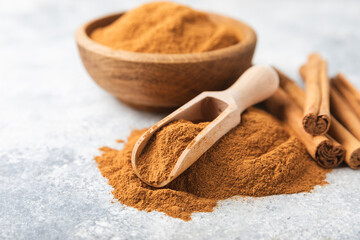 Cinnamon powder on a textured wooden background. Spicy spice for baking, desserts and drinks. Fragrant ground cinnamon. Cinnamon stick. Place for text. Copy space.