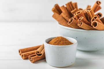 Cinnamon powder on a textured wooden background. Spicy spice for baking, desserts and drinks. Fragrant ground cinnamon. Cinnamon stick. Place for text. Copy space.